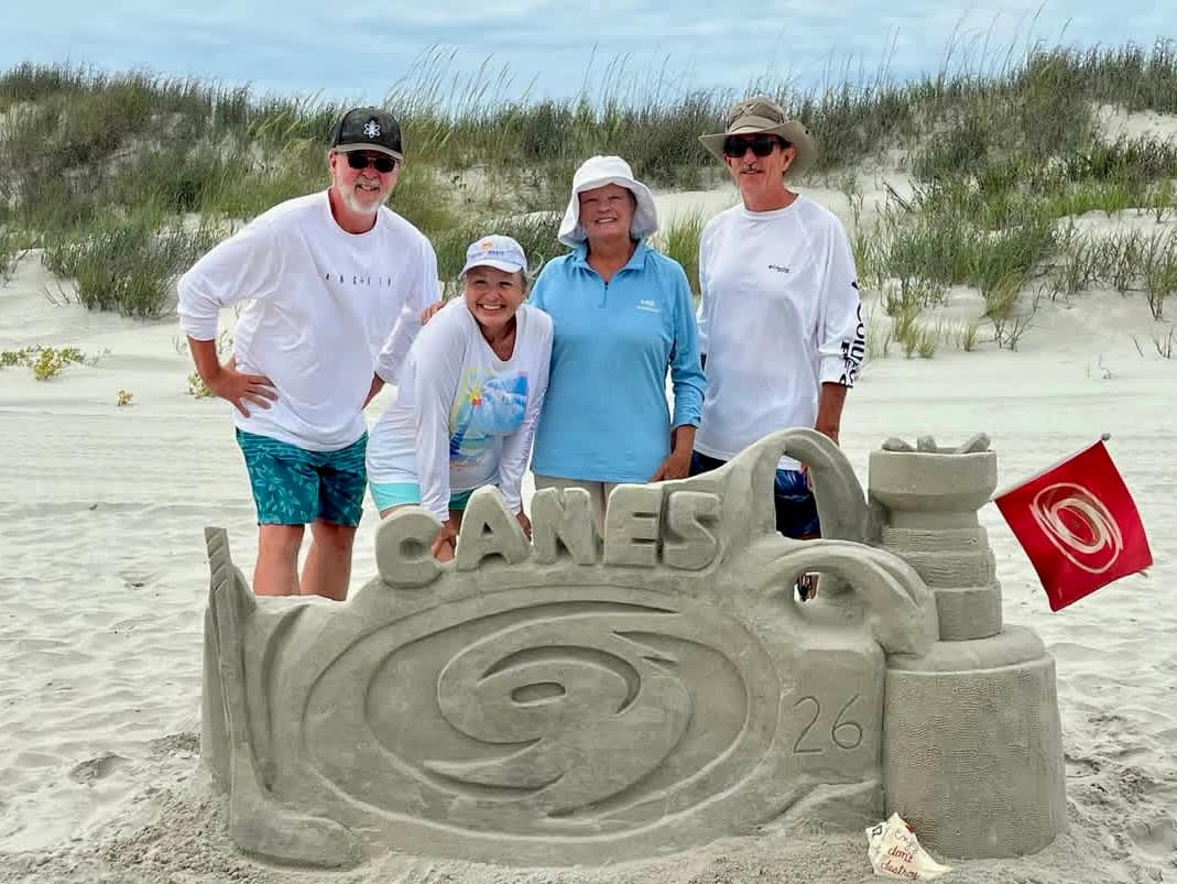 Sunset Sand Artists group posing with their Carolina Hurricanes Stanley Cup sand sculpture at Sunset Beach NC