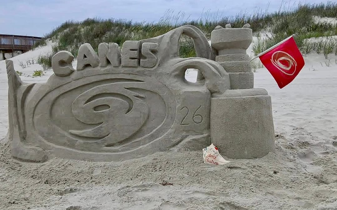 Sunset Sand Artists Hurricanes Stanley Cup sand sculpture at Sunset Beach NC showing Canes logo and 2026 with Hurricanes flag