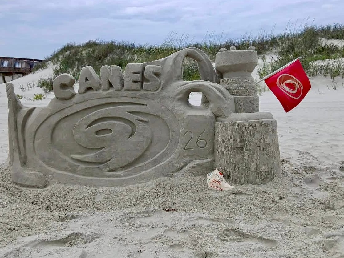 Sunset Sand Artists Hurricanes Stanley Cup sand sculpture at Sunset Beach NC showing Canes logo and 2026 with Hurricanes flag